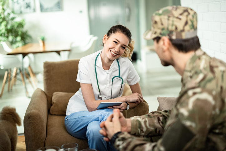 A veteran wearing a uniform, sitting with a nurse.