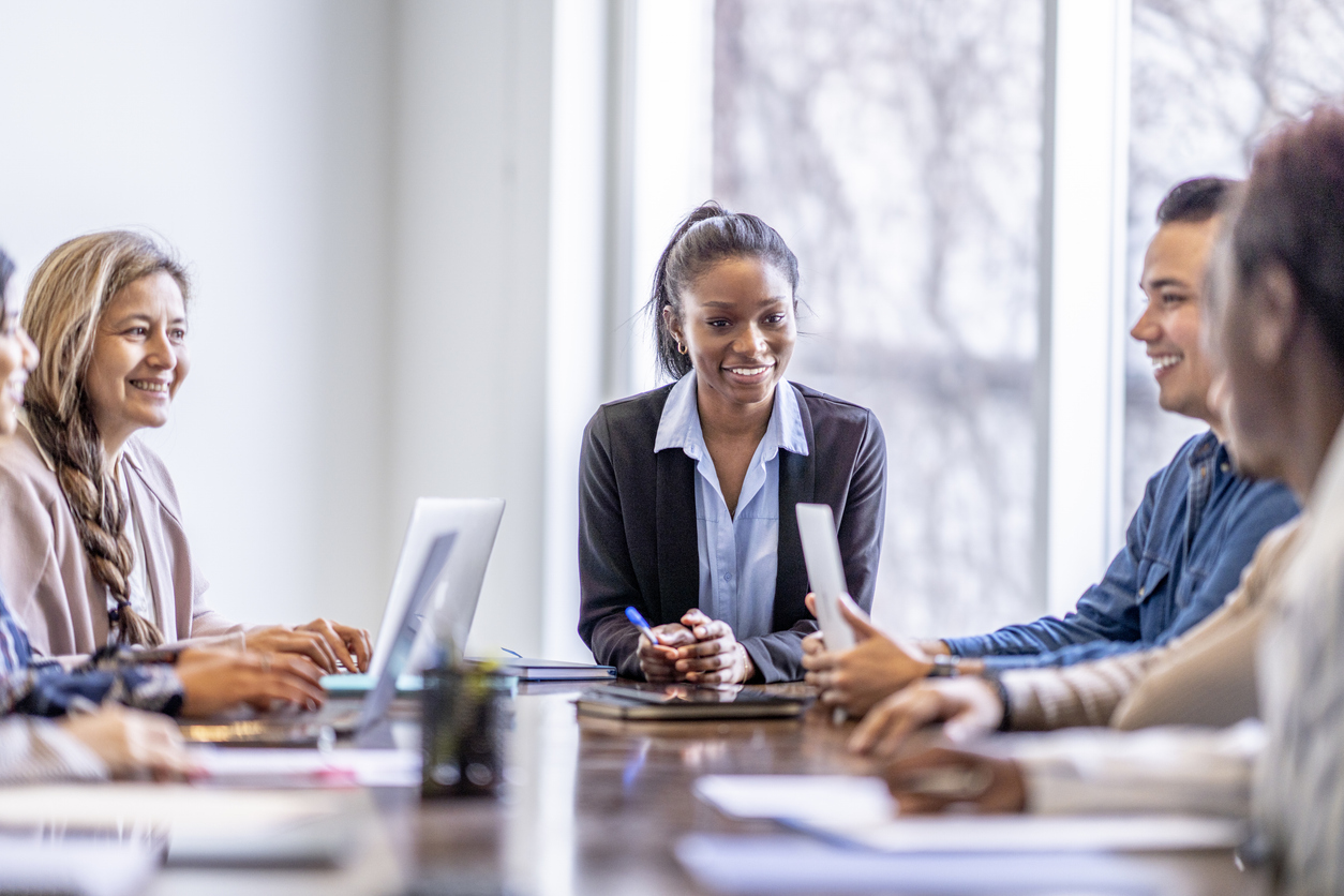 Professionals talking in a business meeting around a conference table.